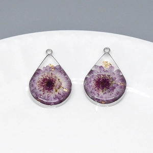 Makroaufnahme der Harzanhänger in Tropfenform mit violetten Trockenblumen und Goldfolie