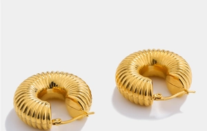 Detail of gold-plated chunky hoop earrings featuring a unique ribbed texture and hinge clasp