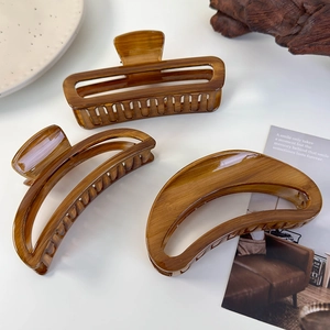 Three tortoiseshell acrylic hair claws in crescent and rectangle shapes on a white desk