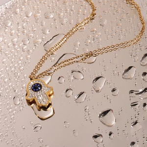 Macro shot of gold Hamsa hand necklace with blue evil eye stone and rhinestones