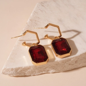 Macro shot of rectangular red zircon earrings with gold plating on light stone