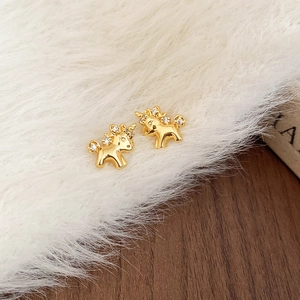 Detail of gold-plated unicorn stud earrings with clear gemstone accents on white fur