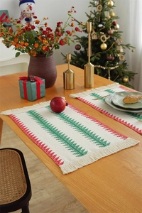 Close-up of woven Christmas table runner with green tree patterns and red zigzag fringes