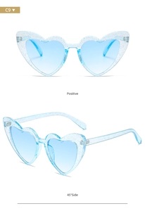 Detail of light blue heart-shaped sunglasses with silver glitter frame and gradient lenses