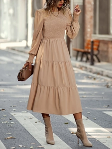 Détail de la robe mi-longue évasée beige avec manches longues et taille cintrée