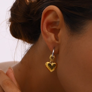 Polished gold heart drop earrings with silver hooks shown on a fashion model