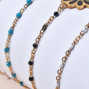 Detailed close-up of golden stainless steel daisy bracelets with blue white black beads