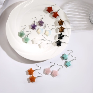 Close-up of star-shaped earrings in assorted colors on a white ceramic plate