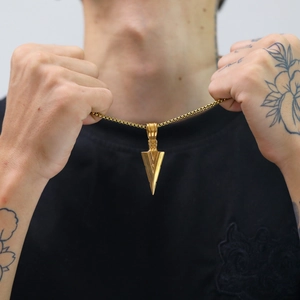 Detailansicht eines goldenen Pfeil-Anhängers mit Box-Kette an einem männlichen Modell
