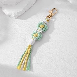 Close-up of handmade macrame daisy keychain with white petals and gold lobster clasp