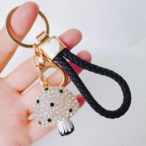 Detail showing crystal mushroom keychain with black white stripes and braided leather strap