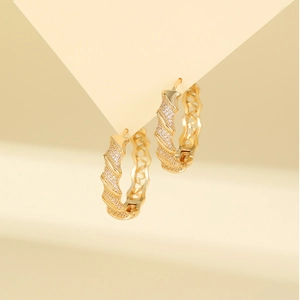 Detail of gold hoop earrings with pavé set cubic zirconia and wavy cutout texture
