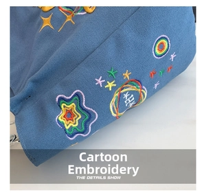 Macro detail showing colorful star and galaxy embroidery on blue canvas tote bag