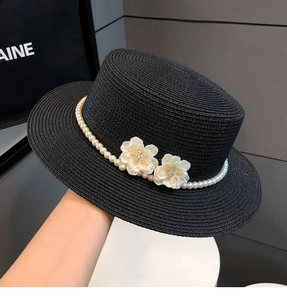 Detail of black straw hat featuring white pearl trim and elegant 3D floral accents