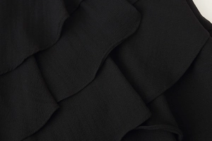 Close-up of black layered ruffle fabric detail showing fine texture and matte finish