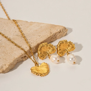 Detail of 18k gold plated ginkgo leaf jewelry set with freshwater pearls on stone