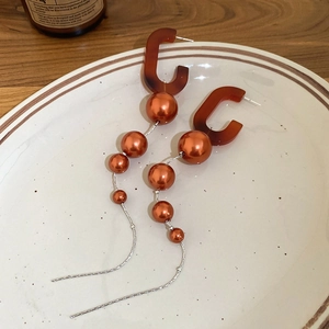 Detail of vintage caramel resin C-shaped drop earrings with warm orange faux pearls