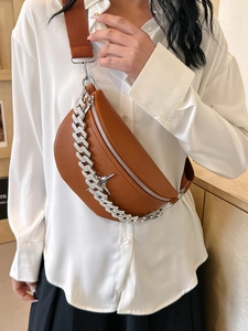 Detail of brown textured leather chest bag featuring silver chain and star charm ornament