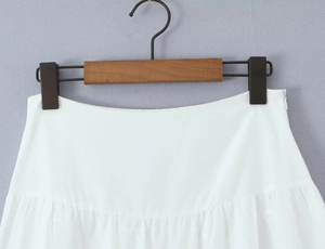 Detail of white pleated skirt featuring a smooth waistline and hidden side zipper