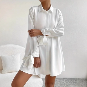 Details des eleganten weißen Satin-Kleids mit schicken Schleifen-Manschetten am Ärmel