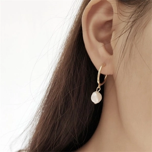 Close-up of elegant golden stainless steel hoop earring with a white baroque pearl on model