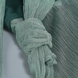 Vue macro détaillée de la texture du tissu plissé vert scintillant et des fibres brillantes