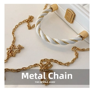 Detailed close-up of golden metal chain and woven handle on the white leather bag