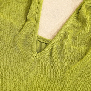 Gros plan sur le tissu en maille côtelée verte et les détails de couture du col en V