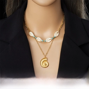 Close-up of double layer necklace with gold conch pendant and turquoise beads