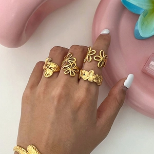 Set of four gold stainless steel floral and leaf open rings worn on a hand