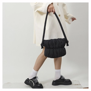Detail of black puffy nylon bucket bag with quilted texture and thick shoulder strap