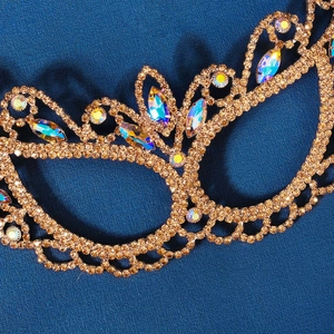 Close-up of gold filigree masquerade mask with marquise rhinestones and luxury sparkle