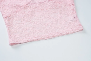 Close-up detail of delicate pink lace hem and intricate floral patterns on a camisole