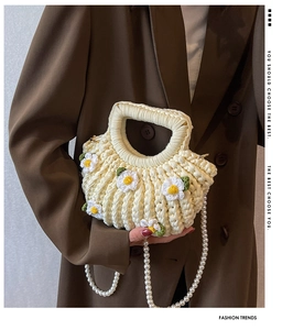 Detail of crochet shell bag with white daisies and elegant faux pearl shoulder strap
