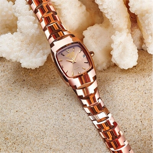 Detail of rose gold quartz watch with square dial and rhinestones on sandy beach background