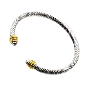 Macro detail of silver cable cuff bracelet with golden spiral accents and round end caps