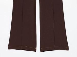 Detail of coffee brown flare pants with yellow contrast stitching and premium fabric texture