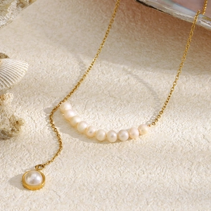 Gros plan du collier en perles plaqué or 18K avec pendentif sur fond de coquillage marin