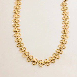 Close-up of interlocking gold titanium steel rings on a minimalist clover necklace chain