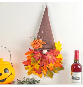 Detail of autumn gnome wall decor with tall brown hat and vibrant fall maple leaves