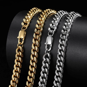 Detailed view of two gold and two silver Cuban link necklaces on a professional display