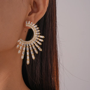 Close-up of luxury gold C-shaped earrings with clear crystals worn by a model