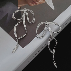 Silver bow ribbon earrings with long flowing metal streamers on a fashion magazine