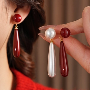 Close-up of elegant red and white teardrop resin earrings worn for a vintage style
