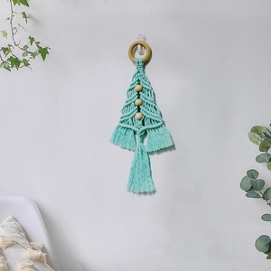 Handmade green macrame Christmas tree wall hanging with wooden beads on a white wall