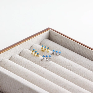 Detailed close-up of gold and silver S925 stud earrings with blue opal and small zircons