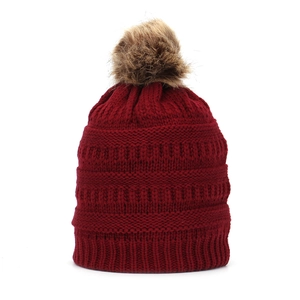 Detailed knit texture and brown faux fur pompom on dark red winter beanie hat