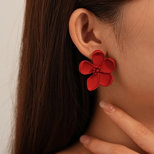 Close-up of elegant red flower stud earrings featuring matte petals and detailed stamens