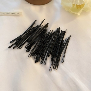 Gros plan de barrettes noires avec pointes rondes sur un tissu texturé blanc