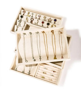 Stack of beige velvet jewelry trays showing organized slots for necklaces and rings